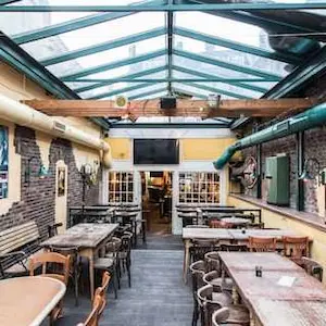 Bar & Kneipe Ocean in Aachen – Großer Innenbereich der Sowiso Ocean Bar mit Holztischen, Holzstühlen und Glasdach