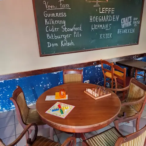 Zwei Brettspiele auf einem Tisch in der gemütlichen Sowiso Ocean Bar Aachen mit Getränkekarte an der Wand