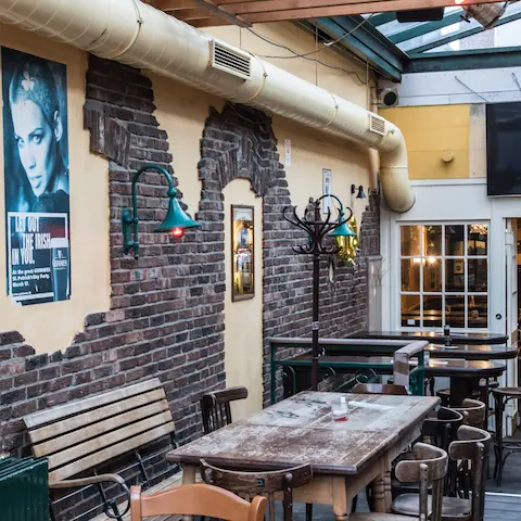 Kneipe & Bar Sowiso in Aachen – Innenbereich mit Glasdach, Steinwand und Holzmöbeln